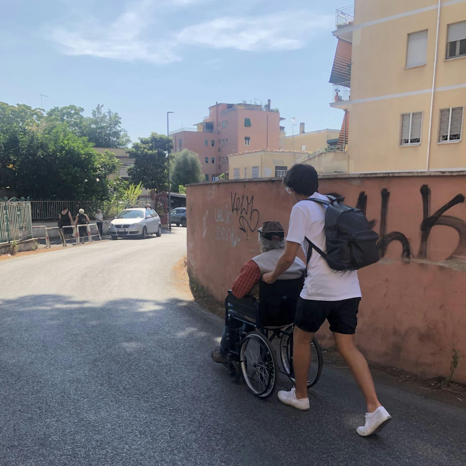 Luca helping an older gentleman in a wheelchair get to his destination